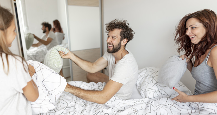 Famille s'amusant dans une chambre avec lit confortable