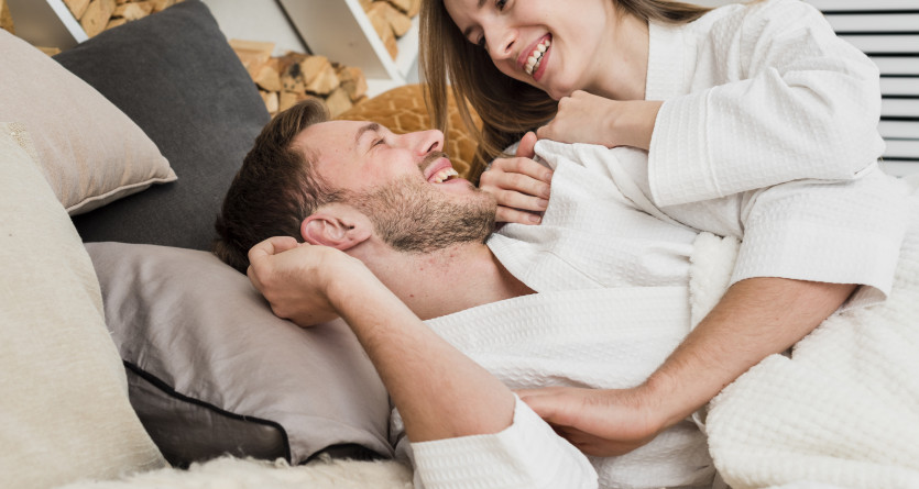 Couple complice en peignoir partageant un moment de d&eacute;tente sur un lit