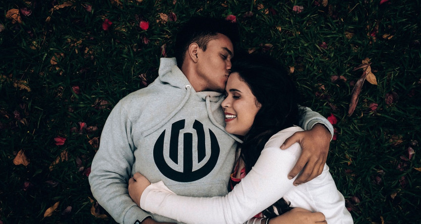 Un couple allong&eacute; dans l'herbe, s'embrassant tendrement et partageant un moment complice