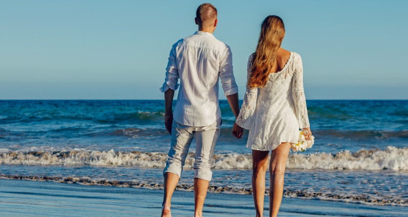 Un couple marchant main dans la main au bord de la mer, partageant un moment romantique