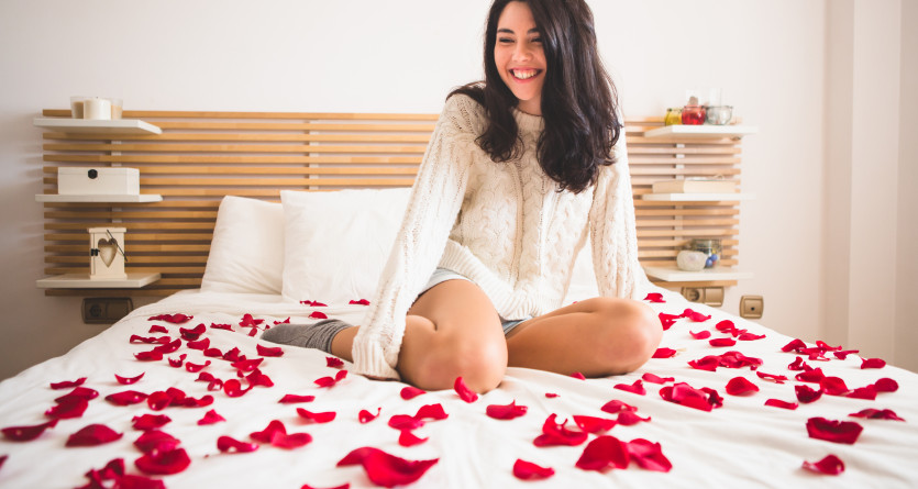 Femme souriante dans une chambre romantique d&eacute;cor&eacute;e avec des p&eacute;tales de roses