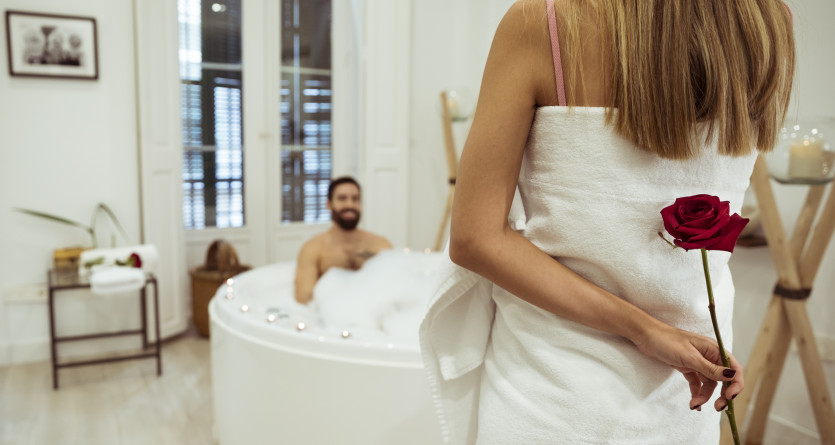 Femme tenant une rose derri&egrave;re son dos dans une chambre avec jacuzzi privatif
