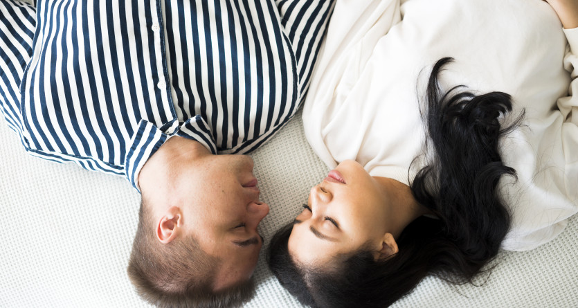 Couple allong&eacute; face &agrave; face, partageant un moment intime et relaxant