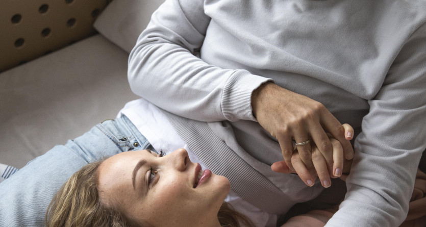 Couple allong&eacute; partageant un moment intime et complice dans une Love Room cosy.