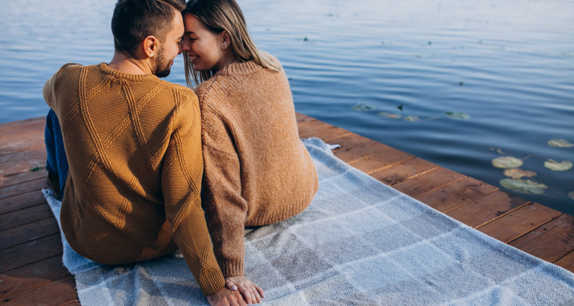 Couple assis au bord de l'eau main dans la main, ambiance romantique