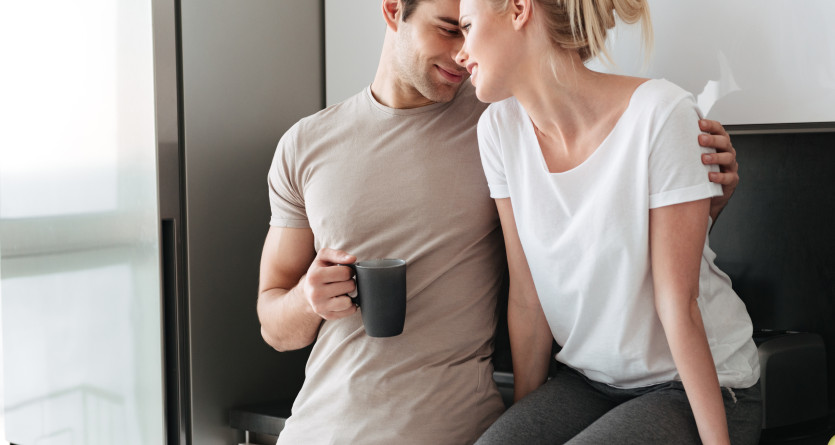 Couple souriant et complice dans une cuisine, partageant un moment intime et d&eacute;contract&eacute;
