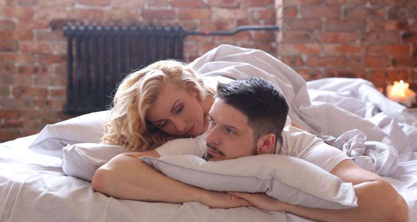 Couple allong&eacute; sur un lit, partageant un moment de complicit&eacute; dans une chambre romantique