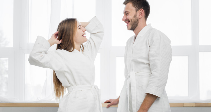 Couple souriant en peignoirs, partageant un moment de d&eacute;tente et de complicit&eacute;