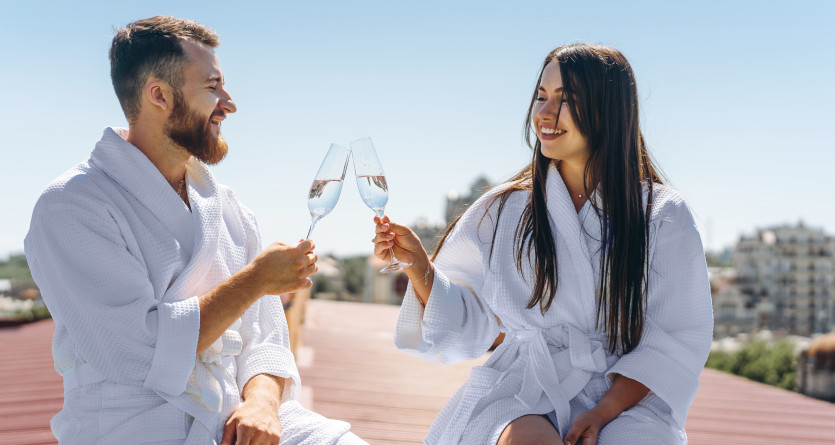 Couple en peignoirs profitant d'un moment romantique sur une terrasse avec des verres de champagne