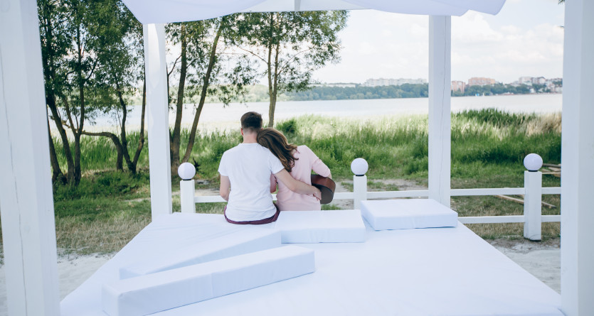 Couple assis ensemble sur un lit ext&eacute;rieur romantique avec vue sur la nature
