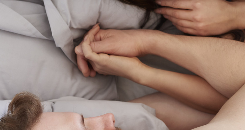 Couple allong&eacute;, main dans la main, partageant un moment de tendresse et de complicit&eacute;