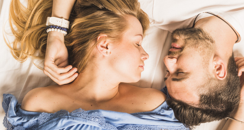 Un couple allong&eacute; t&ecirc;te contre t&ecirc;te, partageant un moment intime et romantique dans une ambiance chaleureuse.