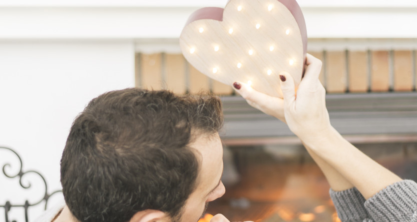 Couple romantique partageant un moment intime devant une chemin&eacute;e avec un c&oelig;ur lumineux.