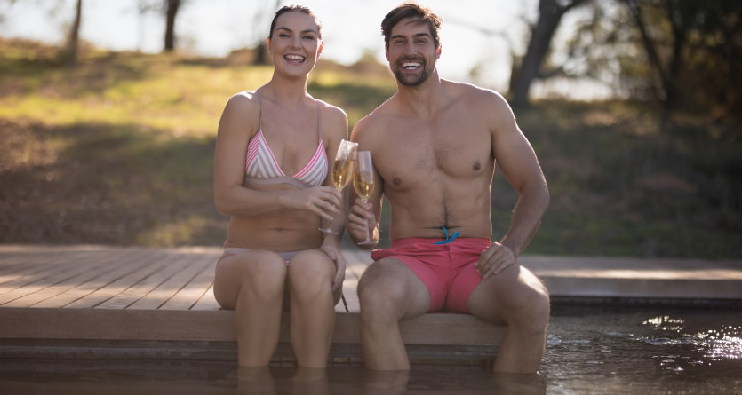 Un couple souriant partage une coupe de champagne au bord d&rsquo;un jacuzzi privatif, id&eacute;al pour une escapade romantique