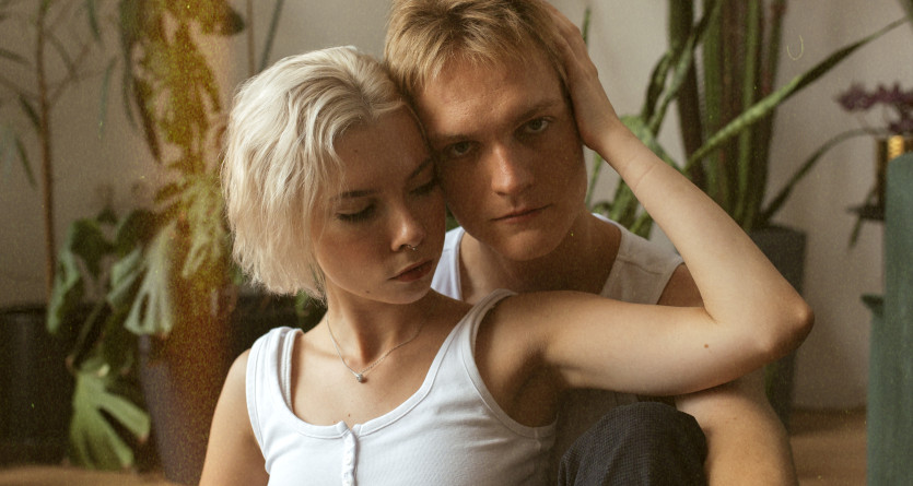 Un couple assis dans un d&eacute;cor naturel et v&eacute;g&eacute;tal, partageant un moment tendre et complice