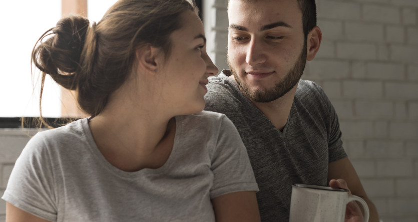 Un couple souriant partage un moment chaleureux et intime autour d&rsquo;un caf&eacute;, dans une ambiance cocooning