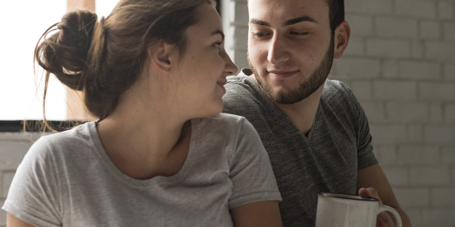 Un couple souriant partage un moment chaleureux et intime autour d&rsquo;un caf&eacute;, dans une ambiance cocooning