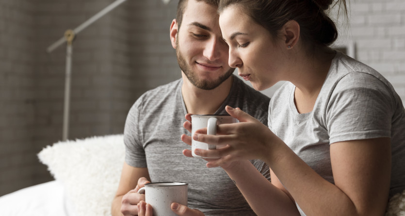 Couple se relaxant dans une chambre romantique avec jacuzzi privatif, tasse &agrave; la main