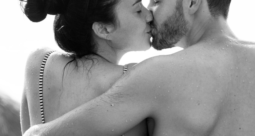 Un couple s&rsquo;embrasse tendrement dans une piscine privative, cr&eacute;ant un moment romantique et intime.