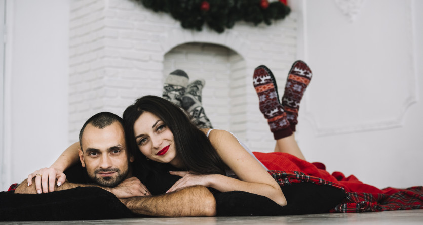 Un couple complice allong&eacute; pr&egrave;s d&rsquo;une chemin&eacute;e d&eacute;cor&eacute;e pour une ambiance chaleureuse et romantique