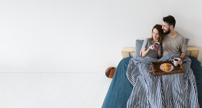 Un couple partageant un petit-d&eacute;jeuner romantique au lit, dans une chambre au style minimaliste