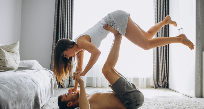 Un couple partage un moment ludique et complice dans une chambre lumineuse au design moderne