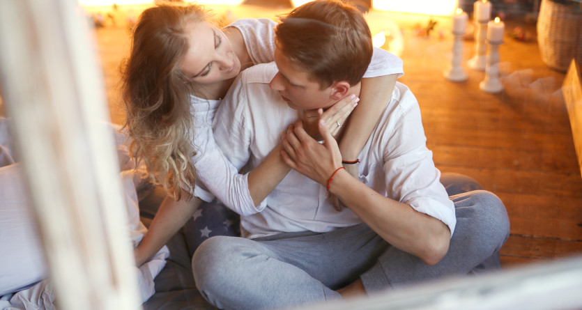 Couple partageant un moment tendre dans une Love Room chaleureuse avec bougies et d&eacute;cor lumineux