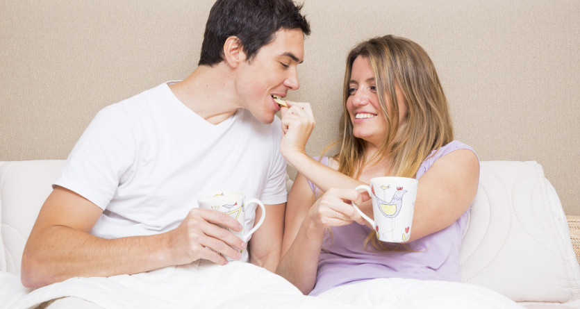 Un couple partage un moment complice en prenant le petit-d&eacute;jeuner au lit