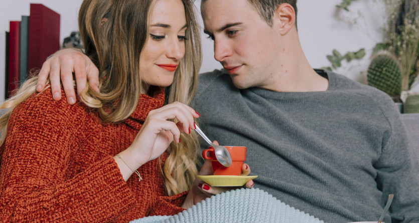 Un couple complice savourant un caf&eacute; sous une couverture dans une ambiance cosy