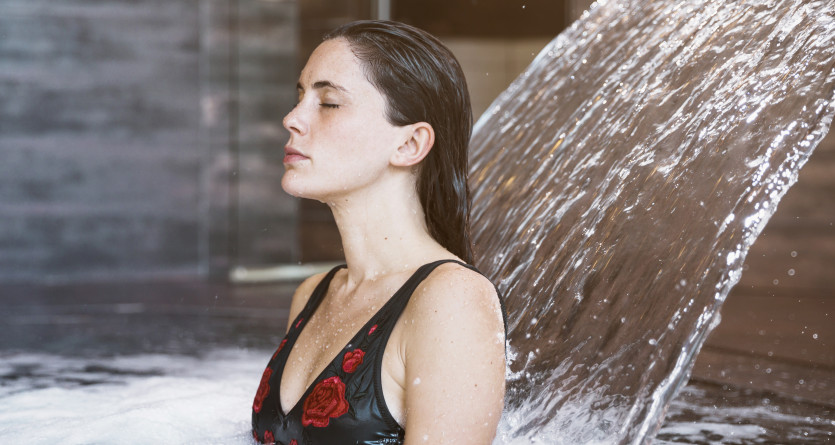Femme profitant d&rsquo;un moment de d&eacute;tente sous une cascade d&rsquo;eau dans un spa luxueux