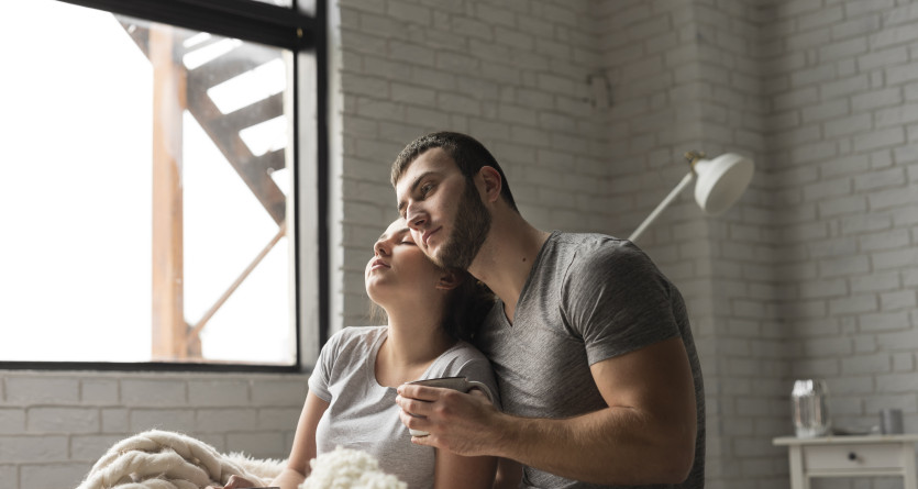 Un couple en d&eacute;tente dans une chambre avec ambiance romantique et lumi&egrave;re naturelle
