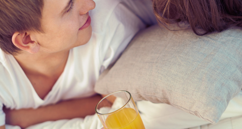 Un couple partage un moment complice avec un petit-d&eacute;jeuner au lit dans une chambre romantique