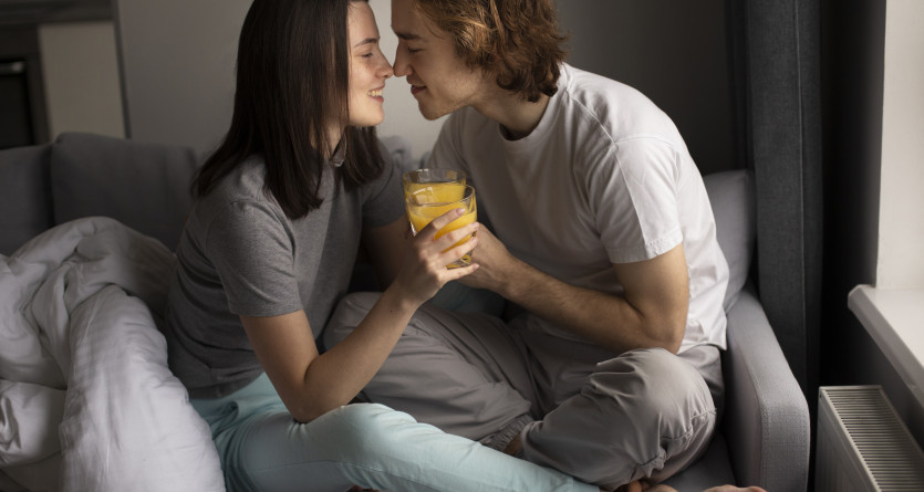 Un couple partageant un moment intime et un jus d&rsquo;orange dans une chambre cosy