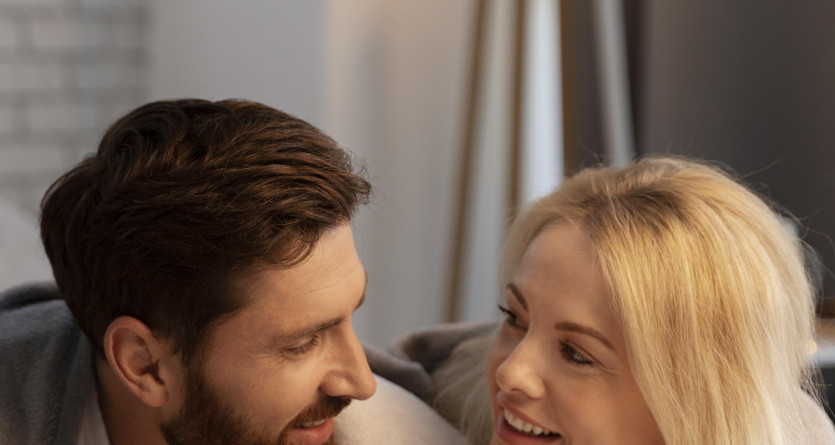 Un couple partageant un regard complice dans une chambre lumineuse et cosy