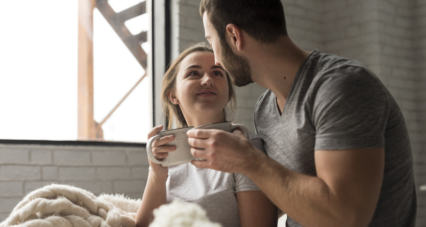 Un couple partage un moment romantique avec une boisson chaude dans une chambre cosy