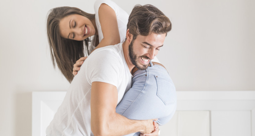 Couple souriant jouant dans une chambre lumineuse, parfait pour une Secret Room d&eacute;di&eacute;e aux exp&eacute;riences sensuelles et ludiques