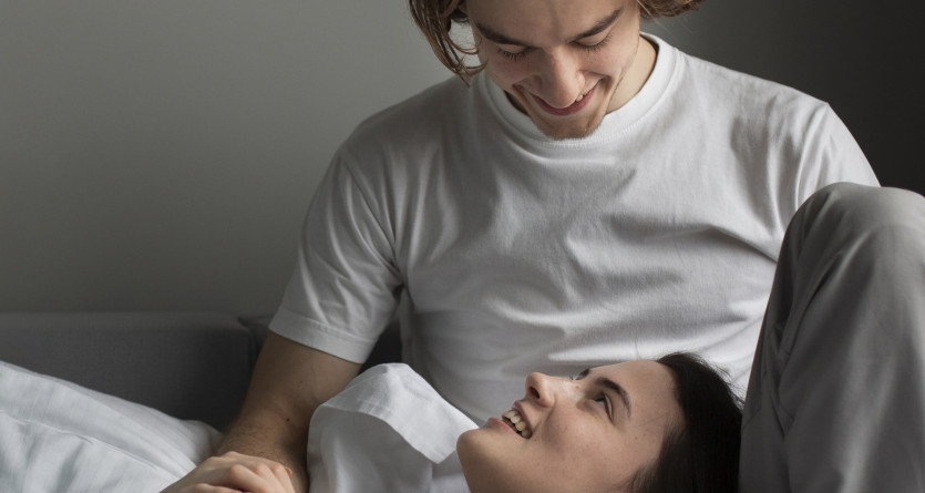Couple souriant allong&eacute; dans une chambre romantique, ambiance intime et relaxante
