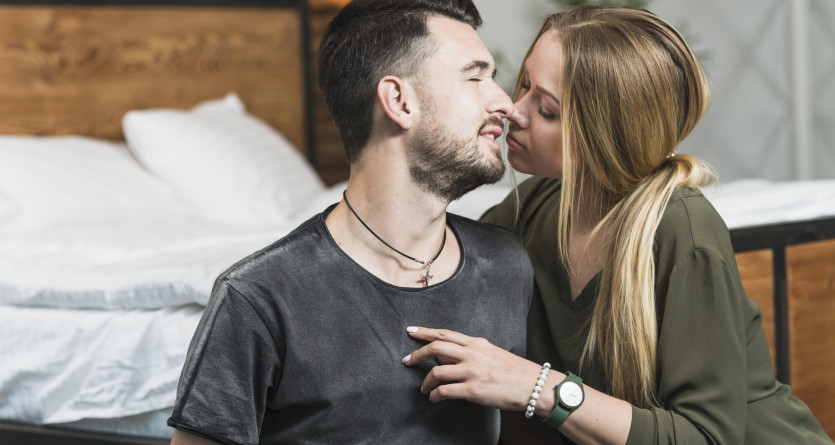 Couple partageant un moment tendre devant un lit dans une chambre romantique &agrave; th&egrave;me