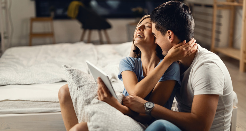 Couple riant et partageant un moment complice dans une chambre cosy