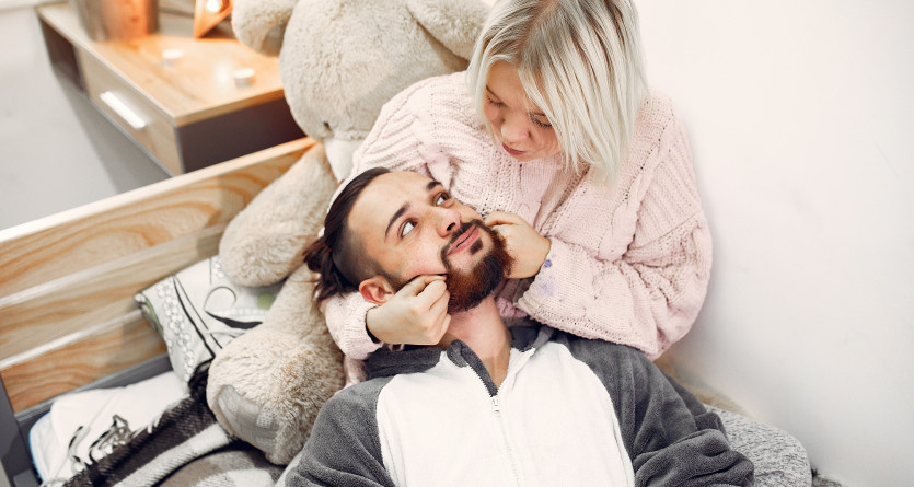 Couple complice en pyjama partageant un moment tendre dans une chambre cosy
