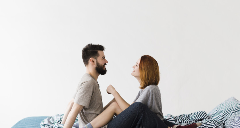 Couple complice assis sur un lit, &eacute;changeant un regard tendre