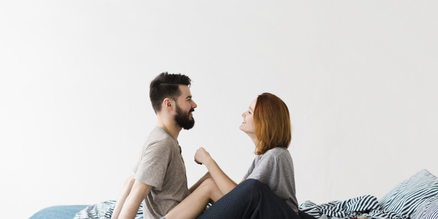 Couple complice assis sur un lit, &eacute;changeant un regard tendre