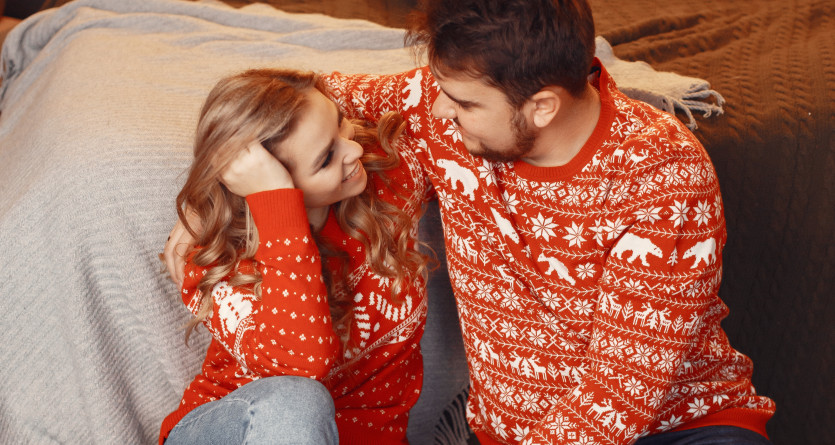 Couple en pulls de No&euml;l partageant un instant romantique dans une Love Room cosy