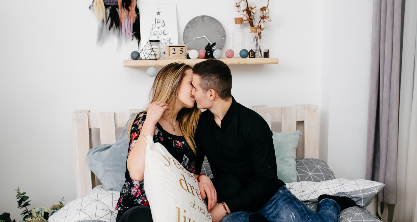 Couple s&rsquo;embrassant tendrement dans une Love Room au d&eacute;cor chaleureux et intime