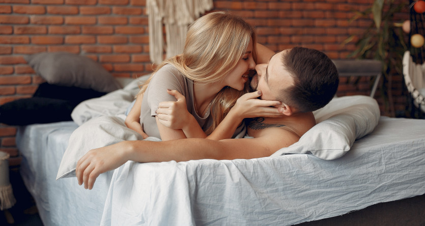 Couple s&rsquo;embrassant tendrement dans un lit, symbole de romance et de complicit&eacute; en Love Room