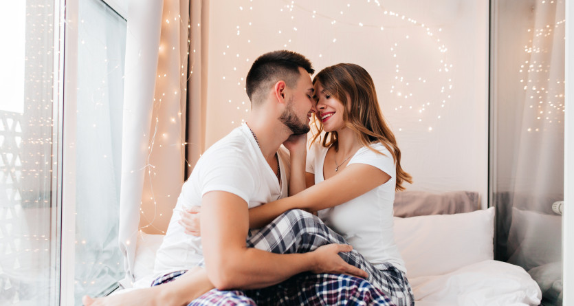 Couple enlac&eacute; sur un lit, entour&eacute; de lumi&egrave;res douces, profitant d&rsquo;un moment intime en Secret Room