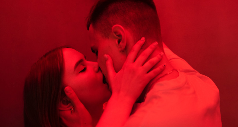 Couple &eacute;changeant un baiser passionn&eacute; dans une ambiance rouge