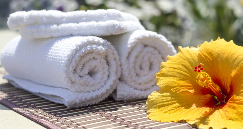 Serviettes blanches roul&eacute;es avec fleur tropicale, invitation au spa