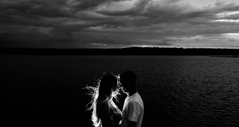 Silhouette d'un couple au bord de l'eau, capturant les derniers rayons du soleil