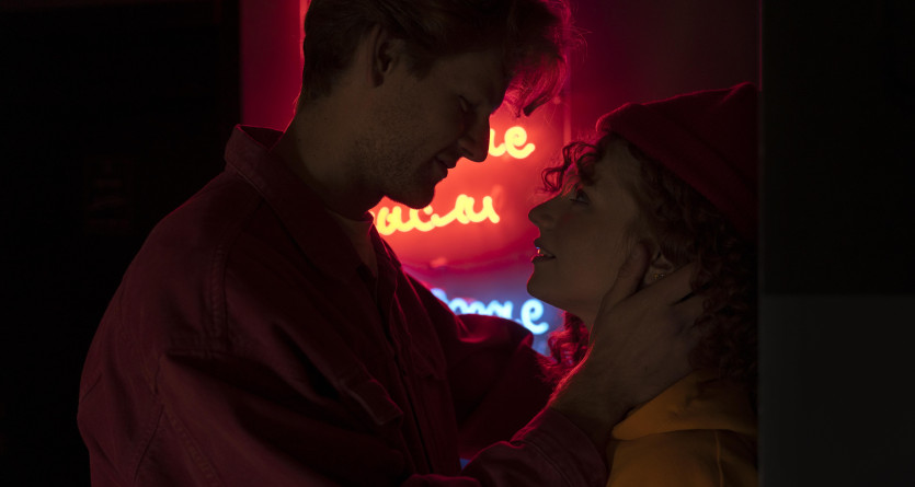 Couple &eacute;changeant un regard tendre sous une lumi&egrave;re n&eacute;on romantique, ambiance Love Room.